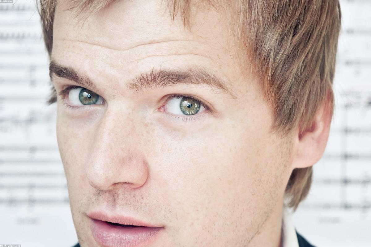 Un giovane direttore d'orchestra sul podio, sala da concerto piena di pubblico